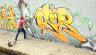 Wide viewof street artist painting colorful graffiti on generic wall - Modern art concept with urban guy performing and preparing live murale with multi color aerosol spray - Retro vintage filter